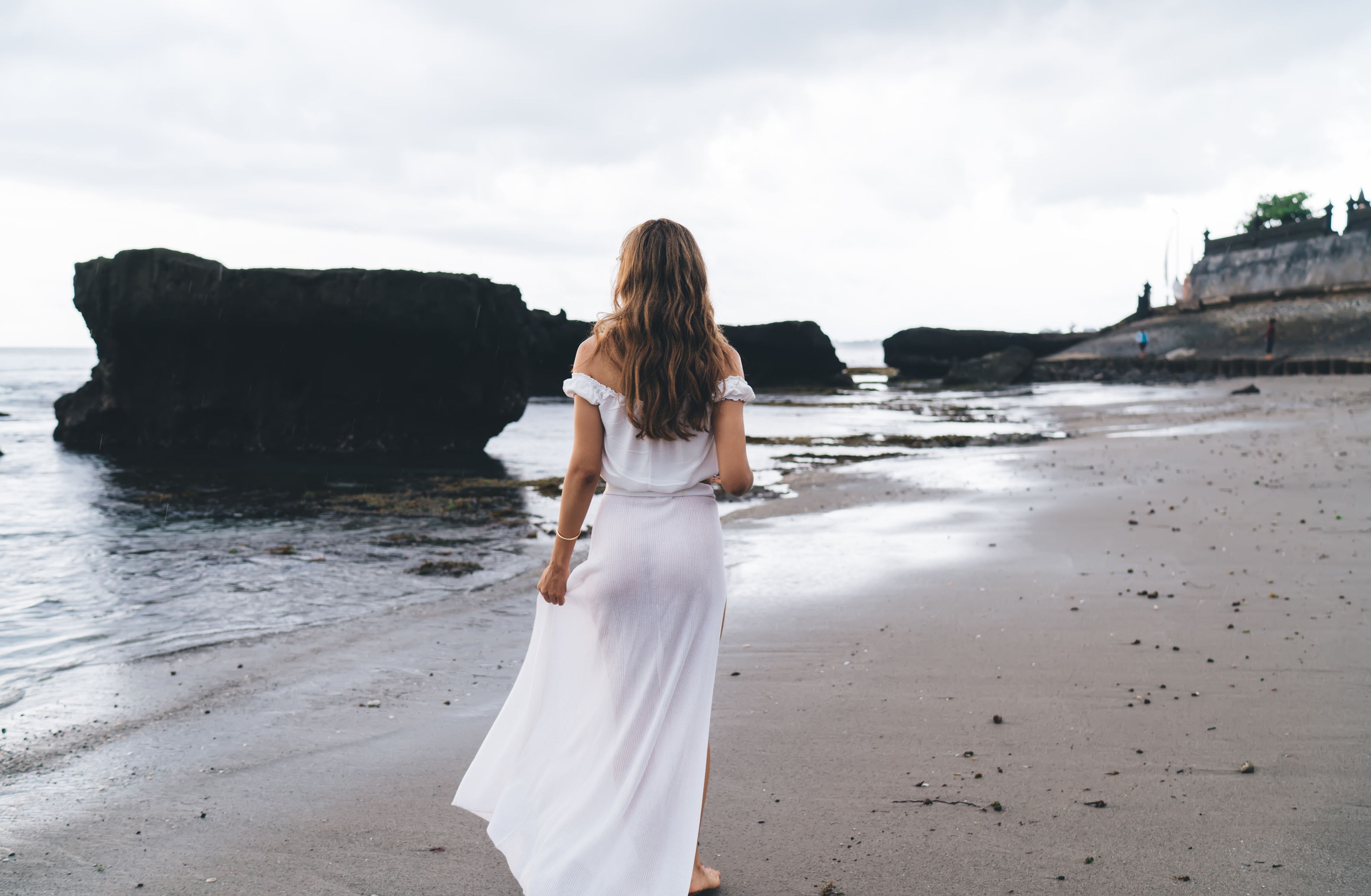 Faceless woman walking along sandy beach